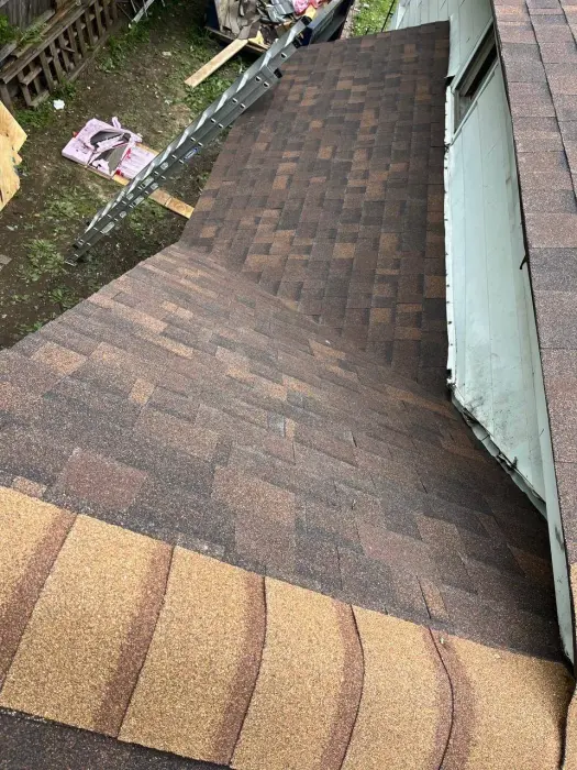 New brown asphalt shingles being installed on a residential roof.