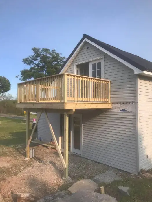 Small house with an elevated wooden balcony and deck.