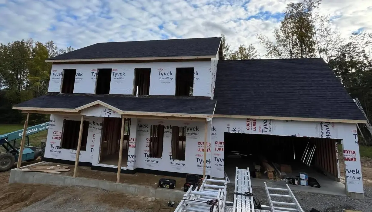 House under construction with Tyvek wrap and shingled roof.