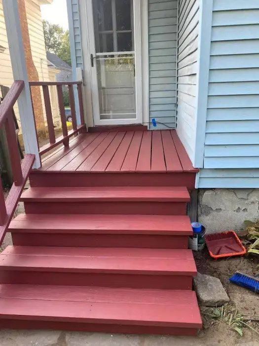 Red wooden stairs leading up to a front porch.