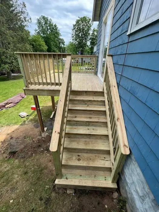New wooden deck and stairs attached to a blue house.
